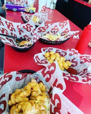 Shrimp Po Boy, Jalapeño Cheesesteak, and Cheeseburger with fries and tots.