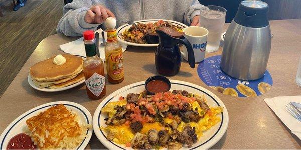 Two: Big Steak Omelettes one with hash browns  one with 4 pancakes.