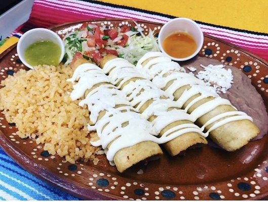 Delicious Fried Crispy Rolled Tacos served with rice and beans . Topped with fresh lettuce, crema , queso cotija.