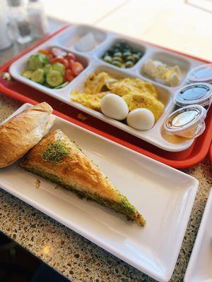 Pistachio Baklava, Omelette with Turkish sausage, boiled eggs, Mixed veggie plate, olives, Peynir (Cheese) Tost, honey, jam, Nutella