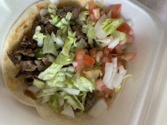 Delicious flour tortilla steak taco with freshly chopped tomatoes and lettuce. The steak is very tender.