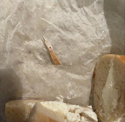 Bagel with piece of wood found inside a bite.