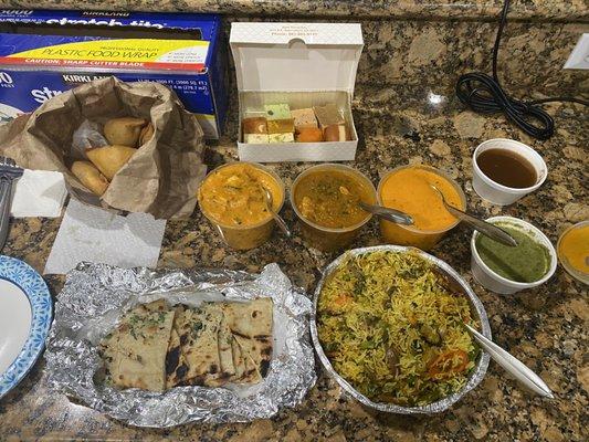 Samosas, Garlic Naan, Paneer Tikka Masala, Chicken Curry, Butter Chicken, Vegetarian Biryani, box of assorted sweets