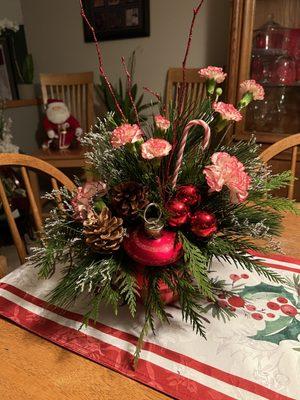 Christmas ornament of seasonal foliage, carnations, pinecones, glass balls and red twigs.