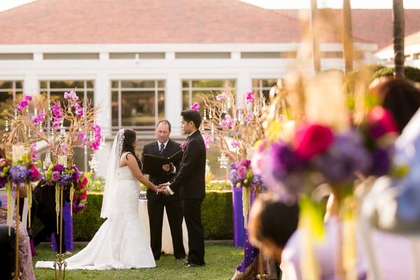 Manzanita trees with orchids for the ceremony, gold cages with flower wreaths and candles lining the aisle