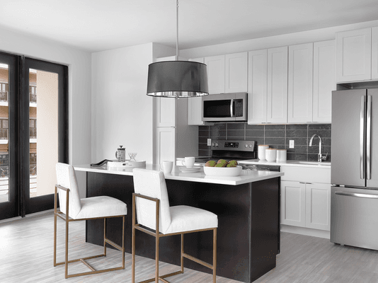 Kitchens featuring chic light fixture, slate appliances, and island with tuck-under countertop for bar stools