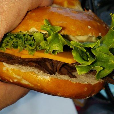 Closer side view of Roast Beef w/ Cheddar Cheese, Mayo, and Lettuce on a Pretzel Bun