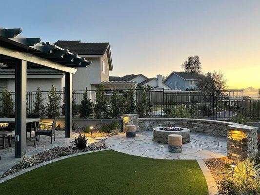 Backyard landscape design and build including seating wall, firepit, patio cover, paver patio, artificial turf and landscaping.