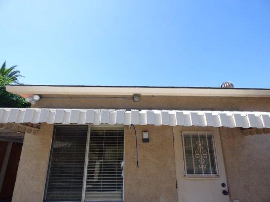 nest located above window awning under roof eaves