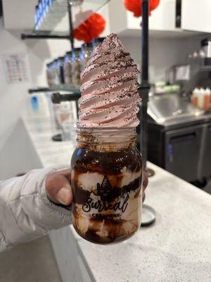 Vanilla ice cream with chocolate and caramel syrup and chocolate crunches on top in a mason jar.