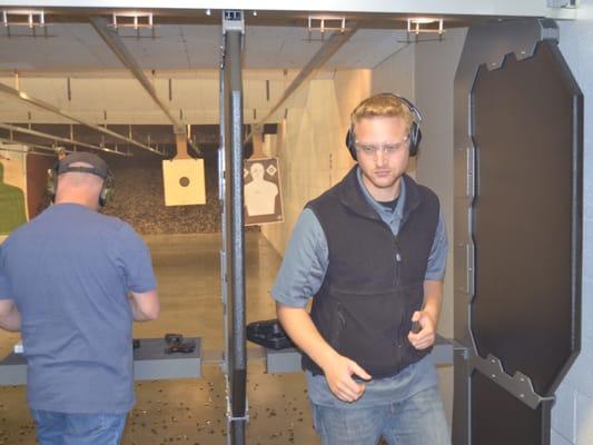 Shooter turns to refill his magazine, safely leaving his pistol in the booth.