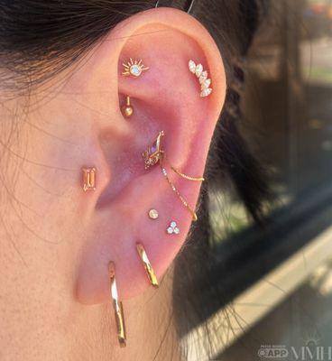 Ear curation with all gold jewelry. Rook, tragus, helix, conch with a chain, and stacked lobe.