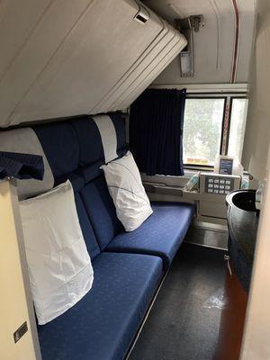 Day time view of sleeping car (there's an extra seat by the window, beside the sink, facing the pillow on the far end)