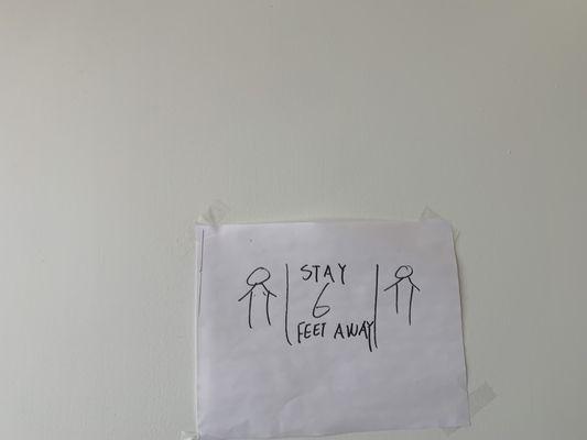 Social Distancing Sign. It is taped to the wall.