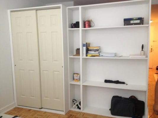 Free standing bookcase wall with a closet.