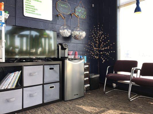 Customer waiting room, with popcorn, TV, Keurig coffee, and beverages in the fridge.