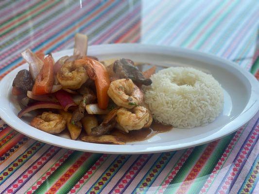 Surf and Turf Saltado: A stir-fry that combines Shrimp and beef, onions, tomatoes, and french fries.