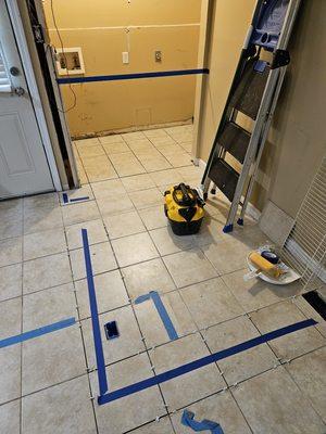 Tile installation in laundry area, and replacing tiles under blue tape from wall removal.