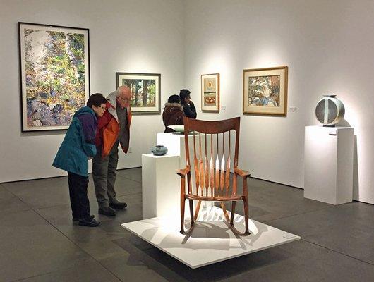 Visitors looks at a chair by Sam Maloof in the ReGeneration exhibition.