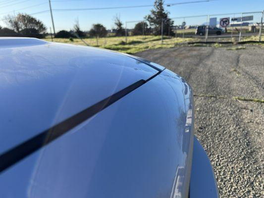 Aftermath of pole falling on hood causing diagonal dent across hood/bumper