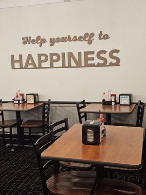 The seating area of the restaurant with a wonderful saying on the wall.