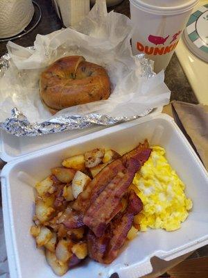 2 eggs breakfast special with bacon, home fries, and blueberry bagel.