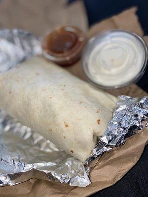 Roburrito with steak , side of hot sauce and sour cream