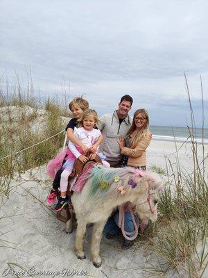 A fun picture of Trigger as a unicorn with a family by the beach.