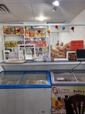 Counter where drinks and desserts are served. A couple of freezers with natural flavored popsicles.