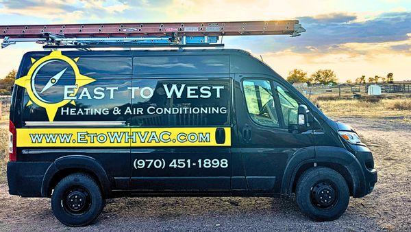 A branded East to West Heating & Air Conditioning service van parked in Greeley, CO, showcasing the company logo and contact ...