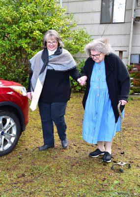 Companion Driver helping a client with a cane to their car.