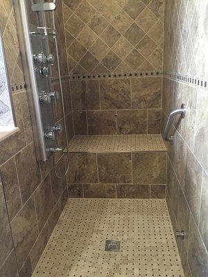 Walk-in shower with cement wet bed floor, mosaic tile floor, and custom shower jet system