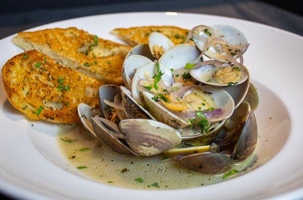 Steamed Clams with garlic bread. Served in a white wine broth with fennel, butter, celery, and lemon.