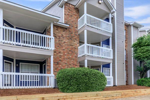 a building with two balconies and a bush in front of it