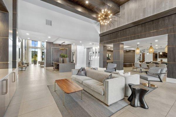 Clubhouse with modern furniture, Apple computers, and seating areas with wall-mounted TVs at Lantower Grande Flats Apartments.