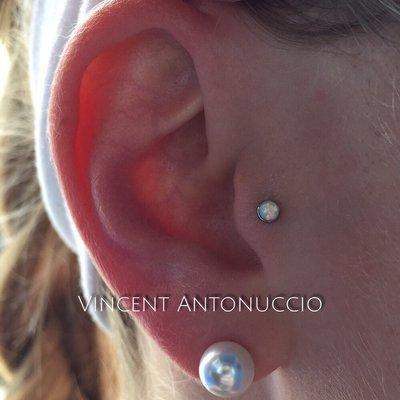 Tragus piercing with a synthetic White Opal.