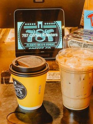 The cups of coffee. A regular oatmilk latte, and a coquito iced latte to the right.