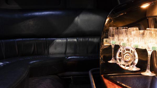 A wraparound leather bench and lighted wet bar highlight the interior of the white Town Car.