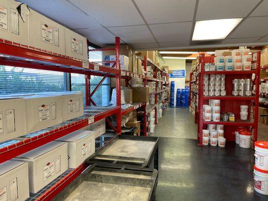 Rows of red shelves stacked with janitorial supplies at Jon-Don San Diego