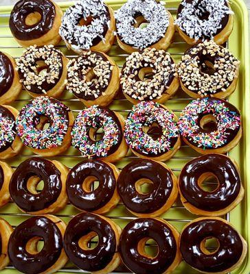 Chocolate iced donuts with sprinkles, peanuts and coconuts