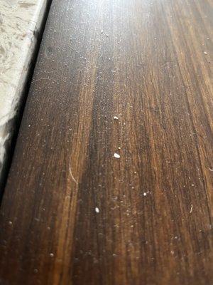 Dust on a wood counter under a box holding napkins, salt & pepper that was never moved or cleaned.