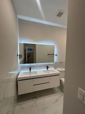 Sleek marble tiles, a chic double sink, and mesmerizing LED mirrors.