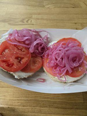 Everything bagel with cream cheese, tomatoes, and pickled onion