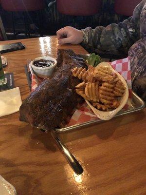 Full rack of baby back ribs with BBQ sauce on the side and Parmesan waffle fries