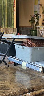 Three filthy bins with cooked ribs wide opened. Chairs leaning against it and flies. Who knows how long they have been sitting there!