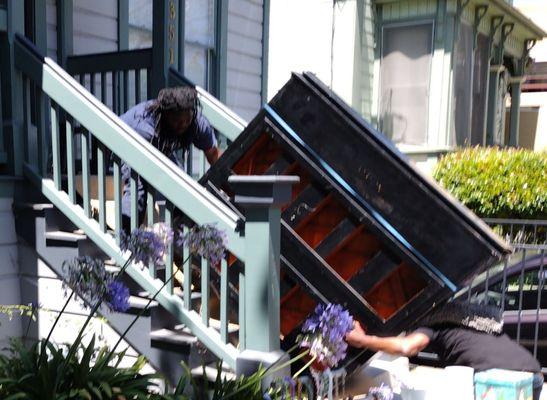 695 pound upright grand piano being carefully moved up the front stairs with no damage to the piano or the stairs.