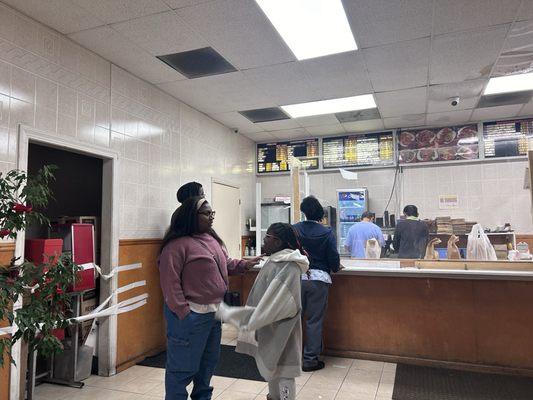 Taped off area where a restroom should be located. Dimly lit and faded menu board. 2020 plexiglass window.