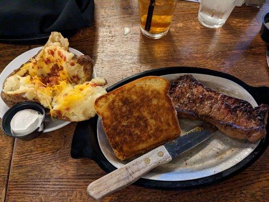 KC Strip with a slice of Texas toast and a twice baked potato.