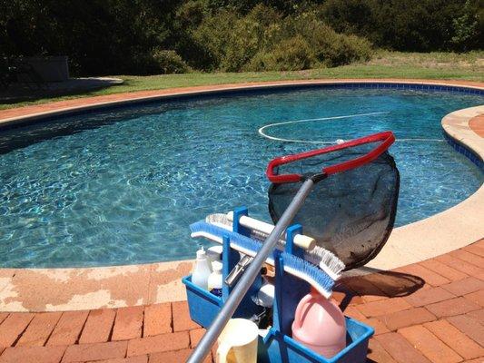 Swimming pool with sparkling blue water reflecting the sun, indicating regular cleaning and chemical treatments for a inviting time