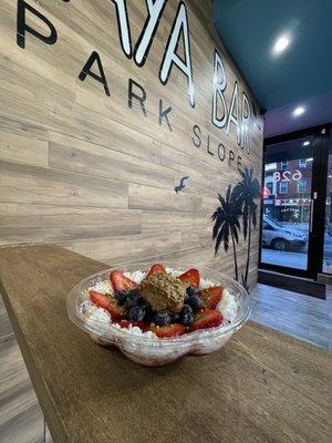 Custom Acai bowl with coconut flakes, strawberries, blueberries, almond butter, honey & bee pollen